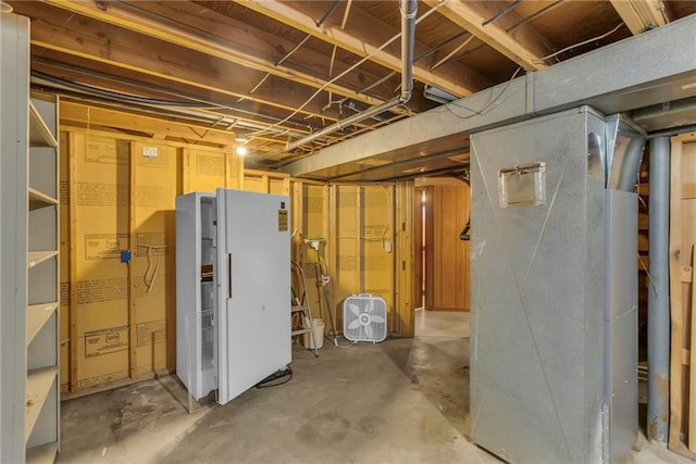 unfinished basement with freestanding refrigerator