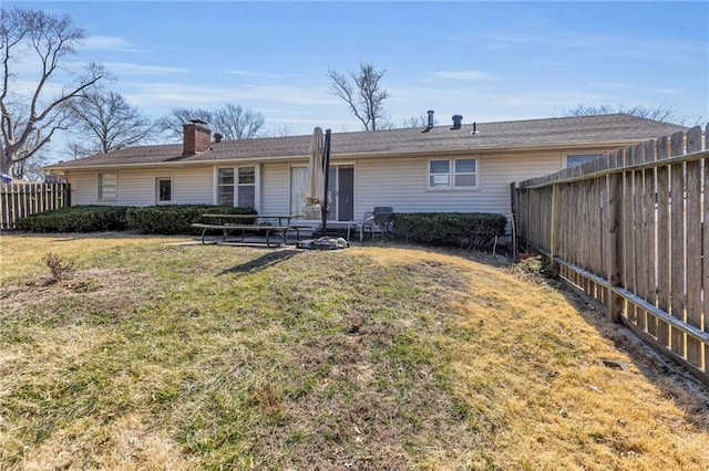 back of house featuring a fenced backyard, a chimney, and a yard