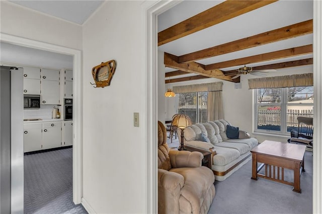 living room with beamed ceiling, ceiling fan, and carpet flooring