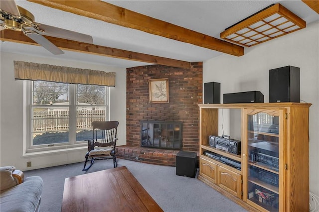 living room featuring a brick fireplace, a ceiling fan, beamed ceiling, and carpet floors