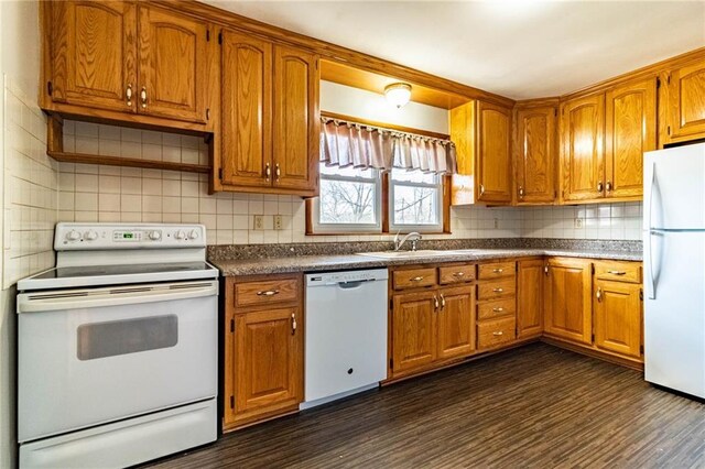 kitchen with a sink, white appliances, and brown cabinets