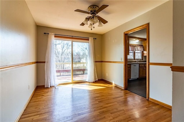 unfurnished room with a ceiling fan, wood finished floors, baseboards, and a sink