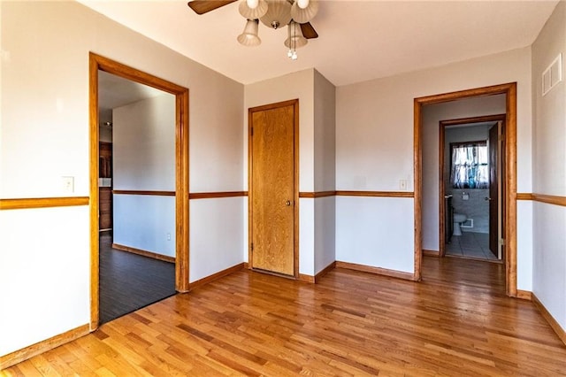 spare room featuring visible vents, a ceiling fan, light wood-type flooring, and baseboards