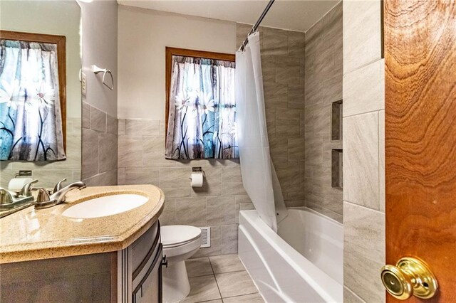 full bath featuring tile patterned floors, toilet, shower / bath combo, tile walls, and vanity