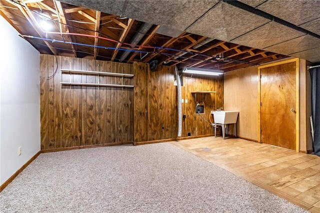 finished below grade area with wooden walls, wood finished floors, baseboards, and a sink