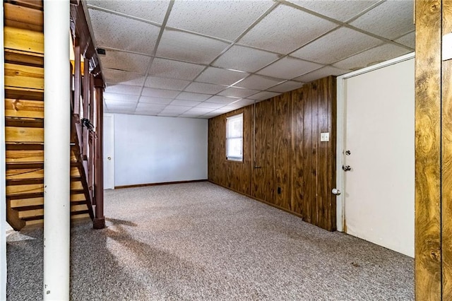 basement with carpet flooring, wood walls, and a paneled ceiling