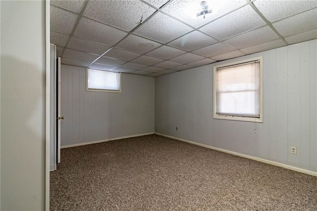 basement featuring a paneled ceiling, carpet floors, and baseboards