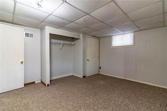 below grade area with visible vents, a paneled ceiling, baseboards, and carpet flooring