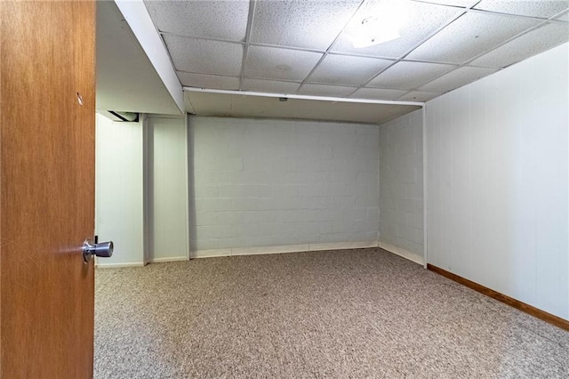 finished basement featuring concrete block wall, a paneled ceiling, baseboards, and carpet floors