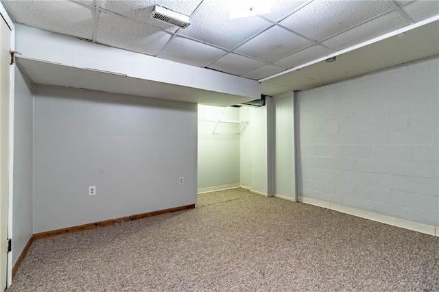 finished below grade area featuring visible vents, baseboards, carpet, concrete block wall, and a paneled ceiling