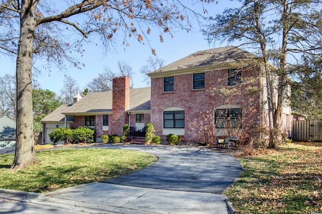 colonial home featuring a front lawn, fence, brick siding, and driveway