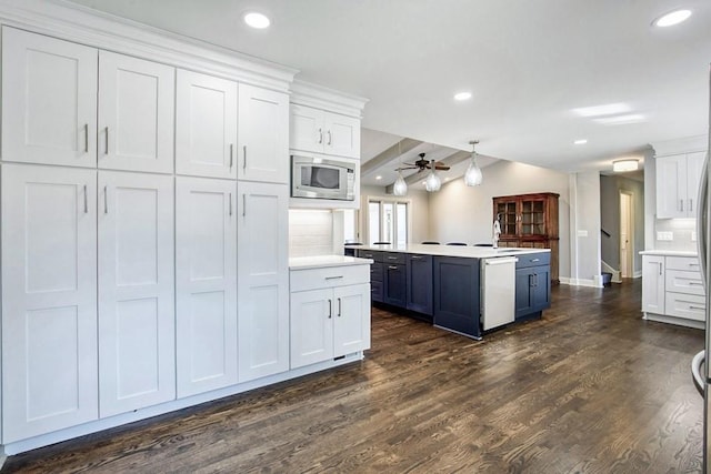 kitchen with stainless steel microwave, dishwasher, light countertops, and a ceiling fan