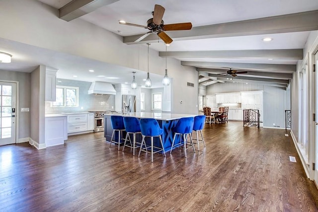 kitchen with vaulted ceiling with beams, ceiling fan, stainless steel appliances, custom range hood, and white cabinetry