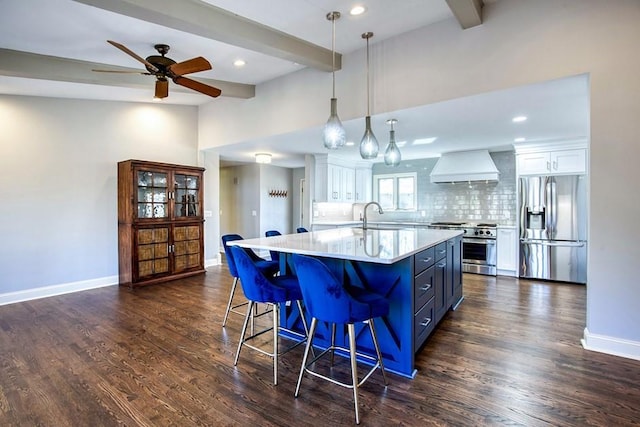 kitchen featuring beam ceiling, appliances with stainless steel finishes, custom exhaust hood, white cabinetry, and a sink