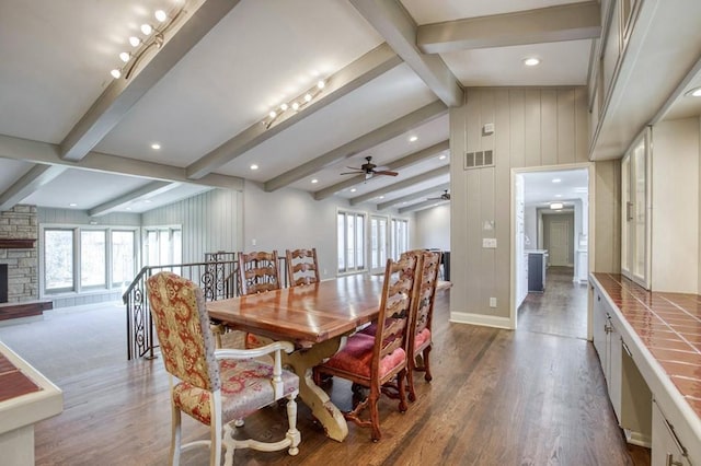 dining area with plenty of natural light, a stone fireplace, ceiling fan, and wood finished floors