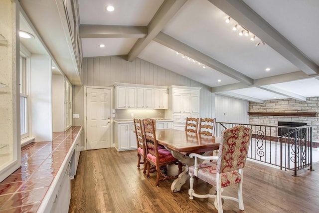 dining space featuring lofted ceiling with beams, wood finished floors, and a fireplace