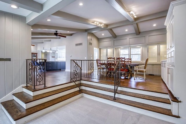 stairway with lofted ceiling with beams, a decorative wall, visible vents, and ceiling fan