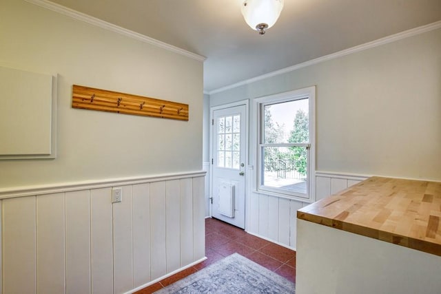 doorway featuring dark tile patterned flooring, a wainscoted wall, and ornamental molding