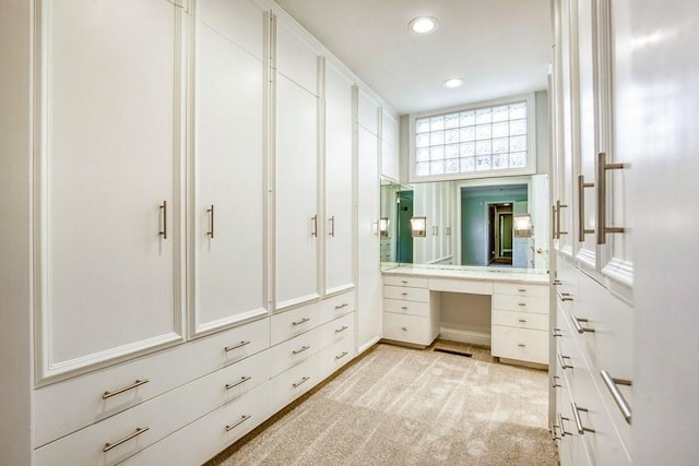 spacious closet with light carpet, visible vents, and built in study area