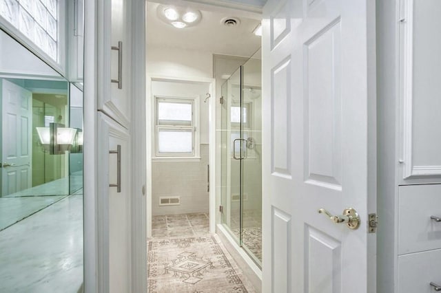 full bathroom with tile patterned floors, visible vents, and a shower stall