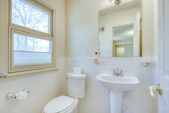 bathroom featuring a wainscoted wall, toilet, tile walls, and visible vents