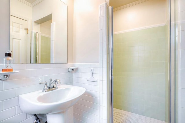 bathroom featuring a stall shower, a sink, ornamental molding, wainscoting, and tile walls