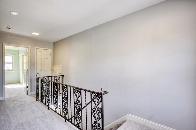 hallway with baseboards, an upstairs landing, and carpet flooring