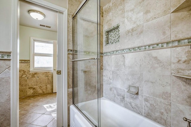 bathroom featuring combined bath / shower with glass door, tile walls, and visible vents