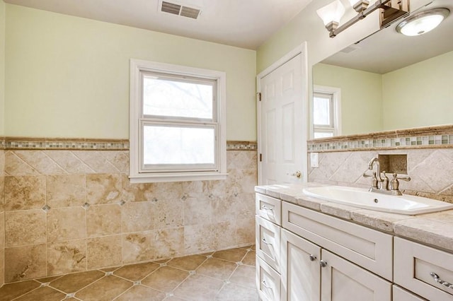 bathroom featuring tile patterned flooring, tile walls, a healthy amount of sunlight, and visible vents