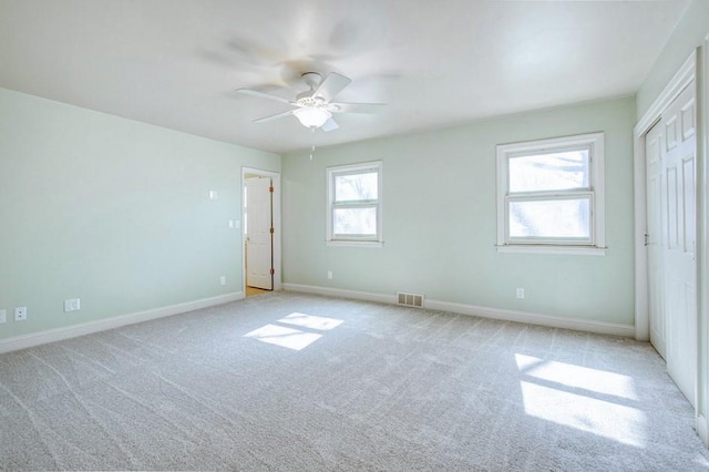 unfurnished bedroom featuring visible vents, light colored carpet, baseboards, and ceiling fan