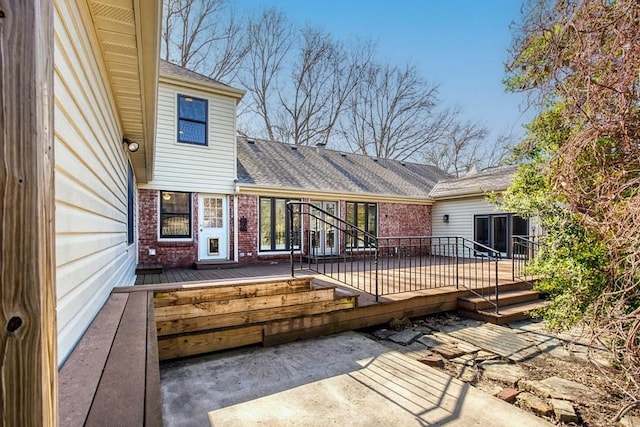 back of property featuring brick siding, roof with shingles, and a wooden deck