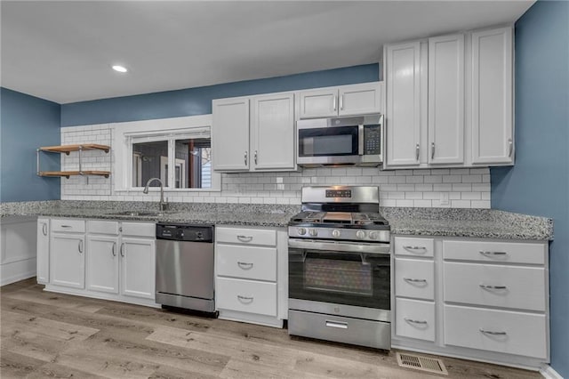 kitchen with white cabinetry, light wood-style floors, appliances with stainless steel finishes, and a sink