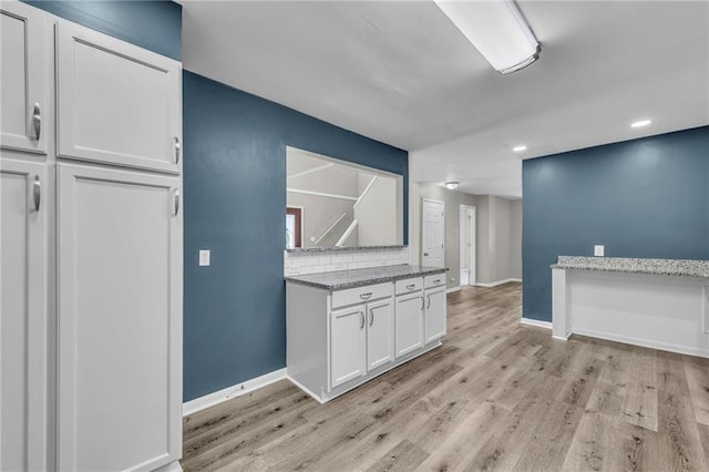 kitchen with baseboards, light wood finished floors, and white cabinetry