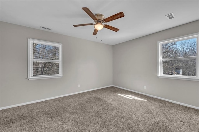 carpeted empty room featuring baseboards, visible vents, and ceiling fan