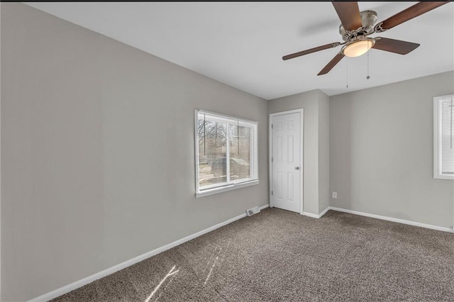 carpeted spare room with visible vents, a ceiling fan, and baseboards