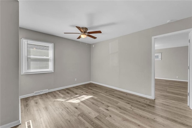 spare room featuring visible vents, baseboards, wood finished floors, and a ceiling fan