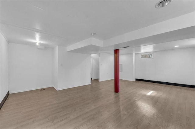 finished basement with visible vents, baseboards, and wood finished floors