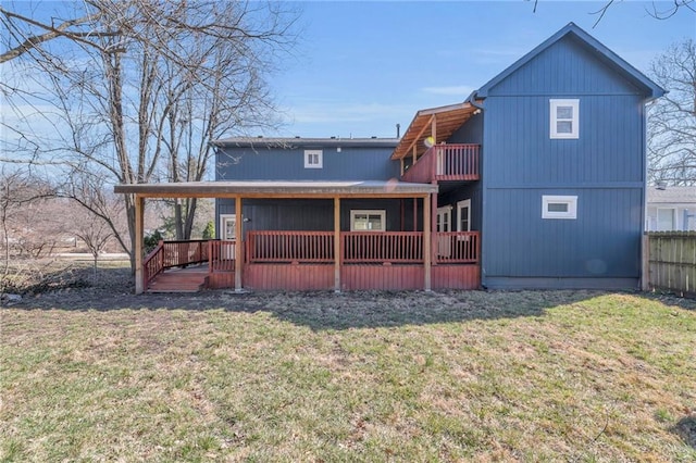 rear view of property with a balcony, a yard, and fence