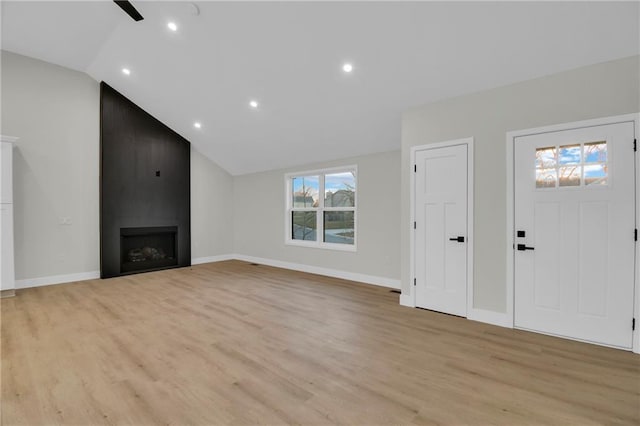 unfurnished living room featuring baseboards, light wood finished floors, a fireplace, and vaulted ceiling