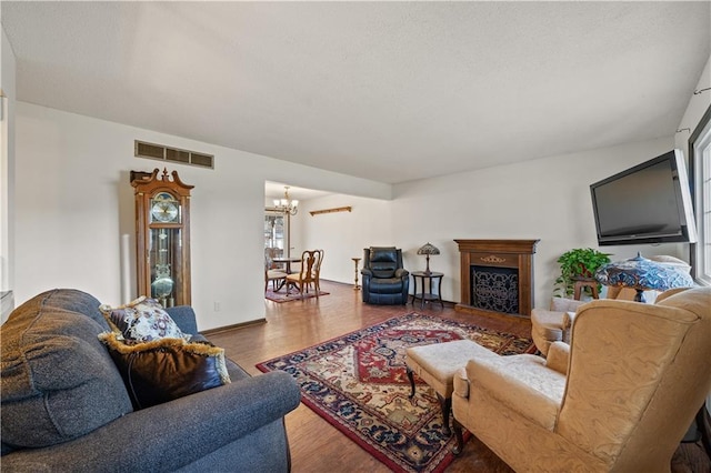 living area with a notable chandelier, visible vents, a fireplace, and wood finished floors