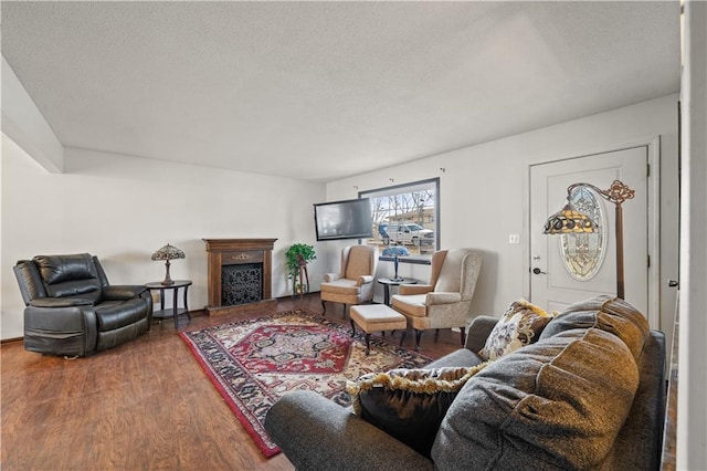 living area featuring a textured ceiling, wood finished floors, and a fireplace