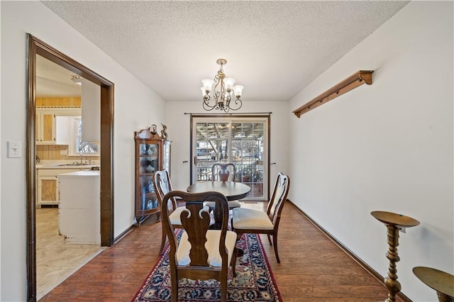 dining room with light wood-style floors, a notable chandelier, and a textured ceiling