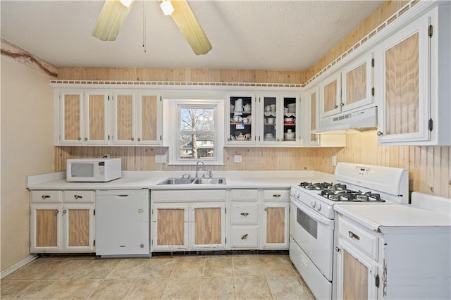 kitchen featuring white appliances, light countertops, under cabinet range hood, and a sink