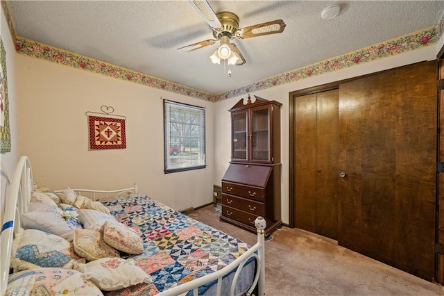 carpeted bedroom with a closet, baseboards, a textured ceiling, and ceiling fan