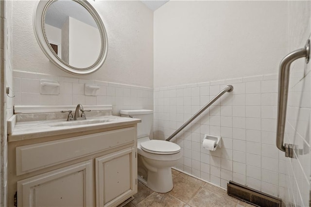 bathroom featuring visible vents, tile walls, toilet, wainscoting, and vanity