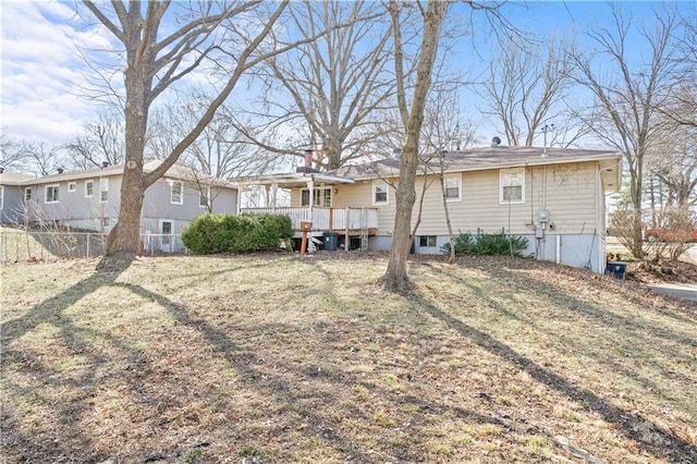 rear view of house featuring a chimney, a lawn, a wooden deck, and fence