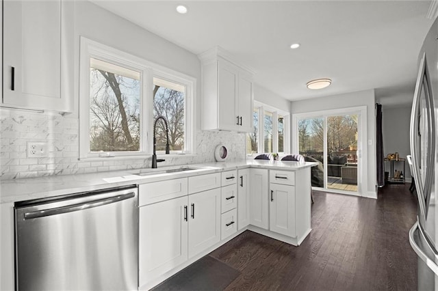 kitchen featuring a sink, backsplash, dark wood-style floors, appliances with stainless steel finishes, and white cabinets