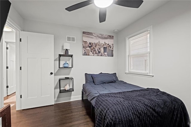 bedroom featuring a ceiling fan, wood finished floors, visible vents, and baseboards