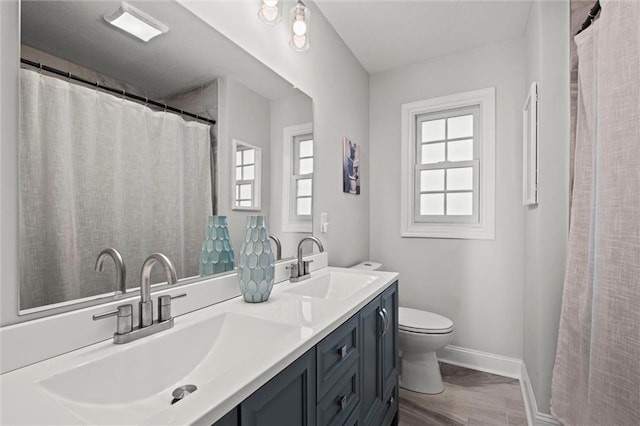 bathroom featuring a sink, baseboards, toilet, and double vanity