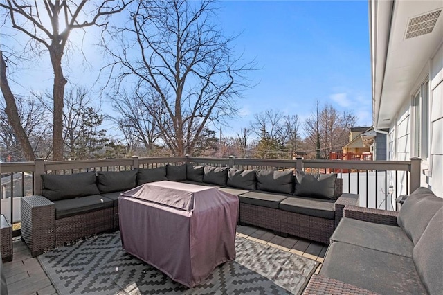 wooden terrace featuring an outdoor living space and visible vents